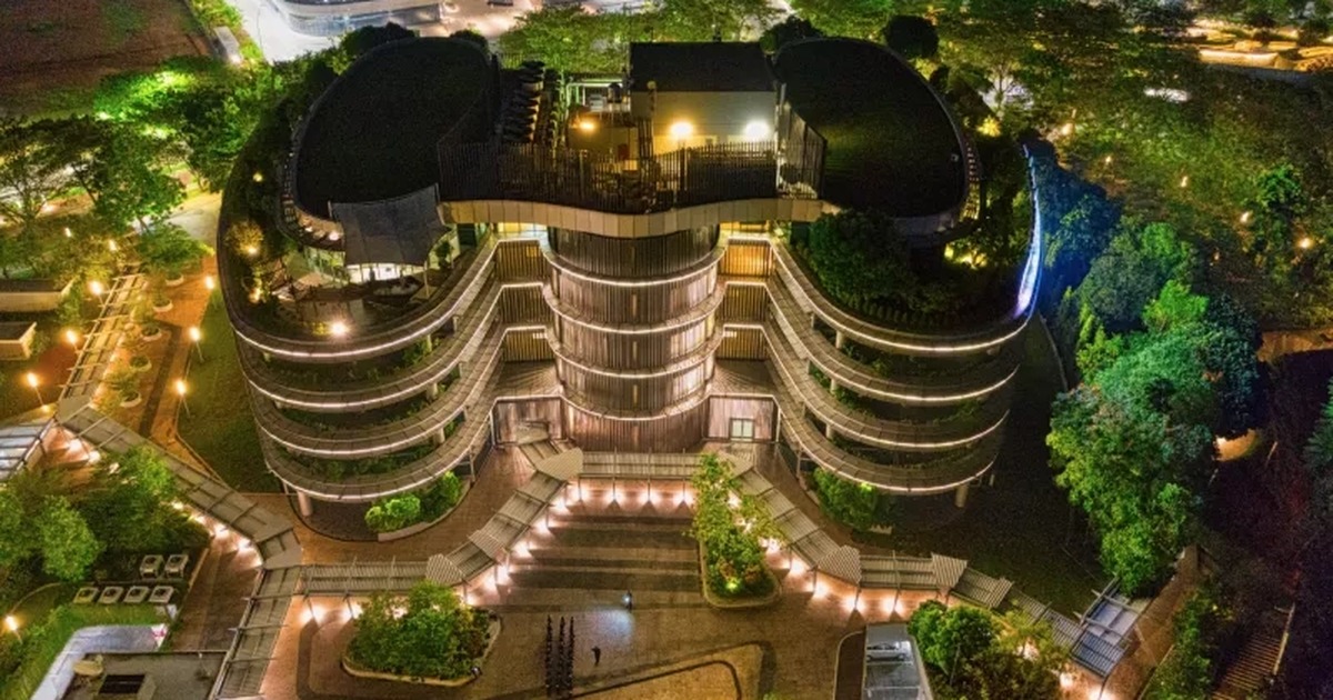 Aerial view of a sustainable hospitality building surrounded by green roofs, gardens, and night lighting.